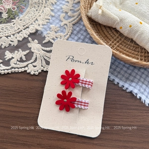 Detail of daisy hair clips with red floral design and red white checkered ribbon wrapping