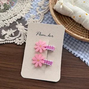 Detail of pink fabric flower hair clips with yellow stamen and gingham ribbon wrap