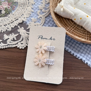 Detailed macro view of cream daisy hair clips with checkered fabric wrapped handles