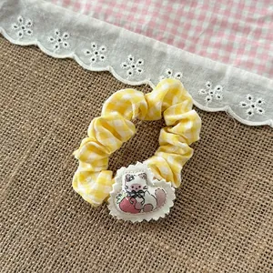 Detail of yellow checkered hair scrunchie with cute cat embroidery and white lace edges