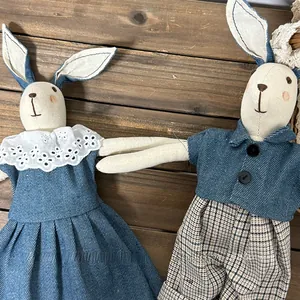Detail view of handmade linen rabbit dolls in vintage floral and denim outfits on wood