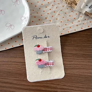 Λεπτομέρεια από κεντημένα ροζ κλιπ μαλλιών cupcake με κόκκινα και λευκά καρό φιόγκους