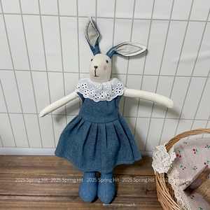 Detailed close-up of a handmade linen rabbit doll wearing a blue denim lace dress