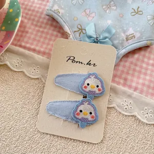 Détail de deux pinces à cheveux en tissu bleu clair avec motifs d'oiseaux brodés