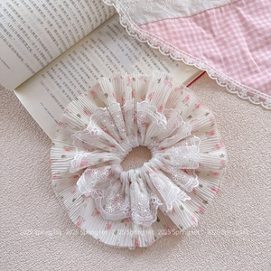 Detailed view of pink floral scrunchie with lace edge on a vintage book background