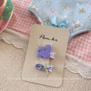 Détail de barrettes brodées chat violet et bouton sur une carte de présentation