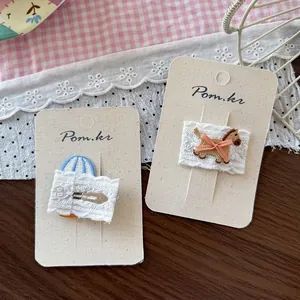 Détail de barrettes en dentelle avec broderie de poney et rayures bleues