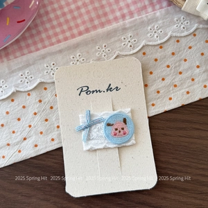 Vue détaillée d'une pince à cheveux à nœud bleu avec broderie d'ours rose