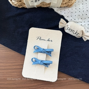 Detail von zwei Jeans-Haarspangen mit Schleifen und Punkten auf einer Displaykarte