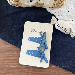 Detailansicht von zwei marineblauen gepunkteten Jeans-Haarspangen auf Karton
