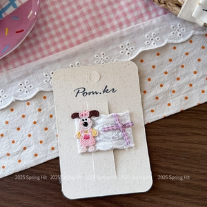 Gros plan sur la barrette brodée chiot avec nœud en dentelle sur un décor printanier doux