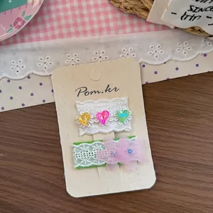 Dettaglio di fermagli per capelli in pizzo con paillettes a cuore e fiori in rete