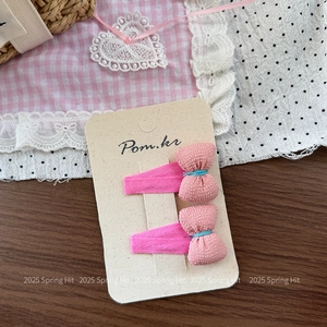 Close-up of pink textured bow hair clips with blue stitching on a branded card