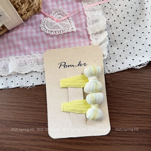 Detail of two yellow striped bow hair clips on natural cardboard with rustic background