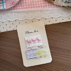 Dettaglio di fermagli per capelli in pizzo ricamato con fiocco rosa e margherita
