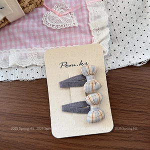 Close-up of two Korean style plaid bow hair clips on a decorative display card