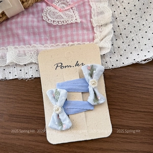 Detail of light blue polka dot bow hair clips with daisy charms on branded display card