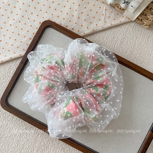 Détail d'un chouchou en tulle blanc à fleurs roses sur un plateau décoratif en bois