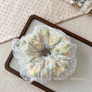 Gros plan du chouchou en maille à pois blancs avec motif floral sur un plateau en bois