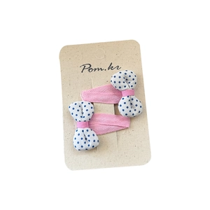 Pink fabric hair clips with blue polka dot bows for girls on a beige card display