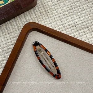 Close-up of tortoise shell pattern oval hair clip with silver metal snap base