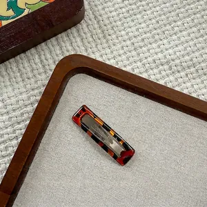 Detail of a rectangular tortoiseshell hair clip with premium acetate texture on a tray