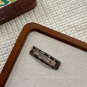 Detailed close-up of tortoise shell resin hair clip on a vintage wooden tray