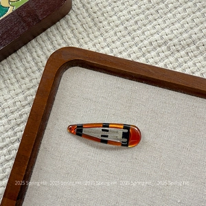 Detailed close-up of retro amber resin hair clip with black stripes and metal clasp