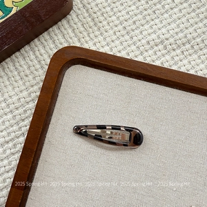 Detailed view of leopard pattern snap clip with polished amber resin on wooden frame