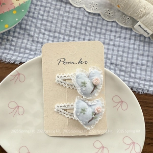 Détail de pinces à cheveux coeur avec broderie florale rose et bordure en dentelle