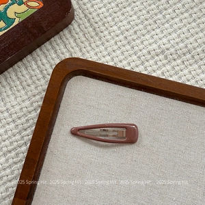 Detail view of a vintage drop-shaped snap hair clip in shiny dark cocoa brown finish