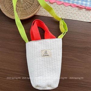 Detailed close-up of quilted cotton bucket bag featuring colorful straps and bear label