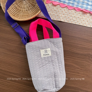 Close-up of quilted fabric bucket bag with cute bear patch on a wooden tabletop