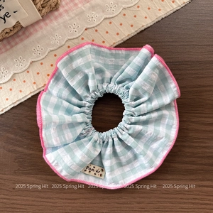Close-up of light blue checkered scrunchie with pink wavy edges and premium fabric texture