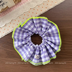 Detail of purple plaid scrunchie with neon green edges and Pom label on wood