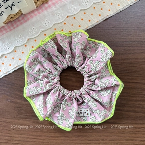 Floral scrunchie with pink patterns and neon green edges on a wood background