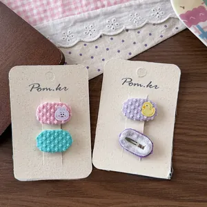 Détail de barrettes brodées pour enfants avec lapin et canard sur tissu décor