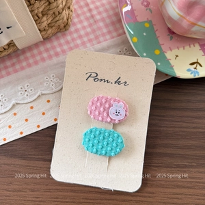 Détail de deux jolies barrettes en tissu avec broderie lapin sur une carte de marque