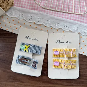 Detail of sweet plaid fabric hair clips with bows and gems on a branded display card