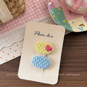 Détail de barrettes en tissu brodé avec motif de cœur et pois sur une carte de marque