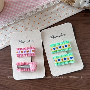 Detail of handmade embroidered heart hair clips on card with pink and green plaid fabric