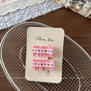 Close-up of handmade pink checkered fabric hair clips with embroidered heart patterns