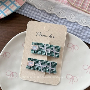 Detailed view of green plaid hair clips with purple resin stone and white ribbon bows