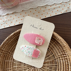 Dettaglio di due fermagli per capelli in tessuto floreale rosa per bambine su carta
