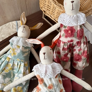 Detail of handmade rabbit dolls in floral dresses with delicate lace embroidery collars