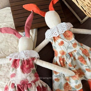 Detailed macro view of linen stuffed rabbit dolls with floral dresses and lace collars