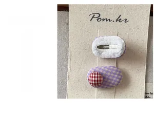 Close-up of sweet purple plaid fabric hair clip with a round bean ornament and metal clip