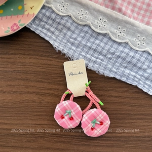 Close-up of pink checkered cherry hair ties on a rustic paper card and wooden table