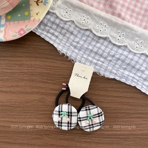 Detail of checkered hair ties with 3D cherry decor on vintage dark wood background