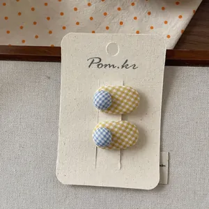 Macro detail of yellow and blue plaid fabric hair clips on a branded display card